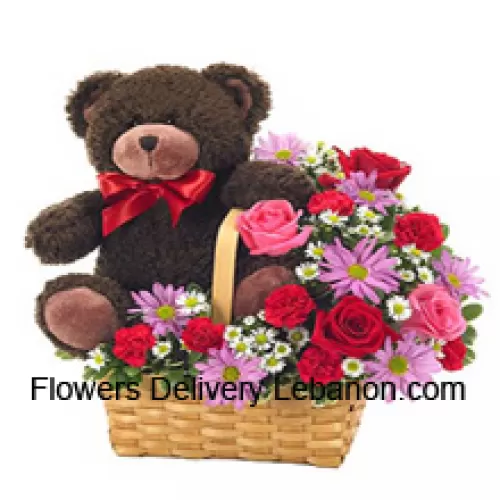 Ein schöner Korb aus roten und pinkfarbenen Rosen, roten Nelken und anderen sortierten lila Blumen zusammen mit einem niedlichen 14 Zoll großen Teddybären