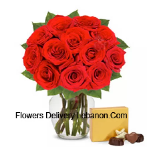 12 rote Rosen mit einigen Farnen in einer Glasvase begleitet von einer importierten Schachtel Schokoladen
