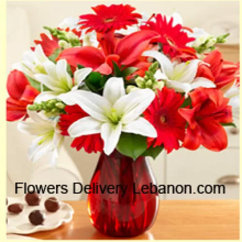 Rote Gerbera, weiße Lilien, rote Lilien und andere bunte Blumen, wunderschön in einer Glasvase arrangiert
