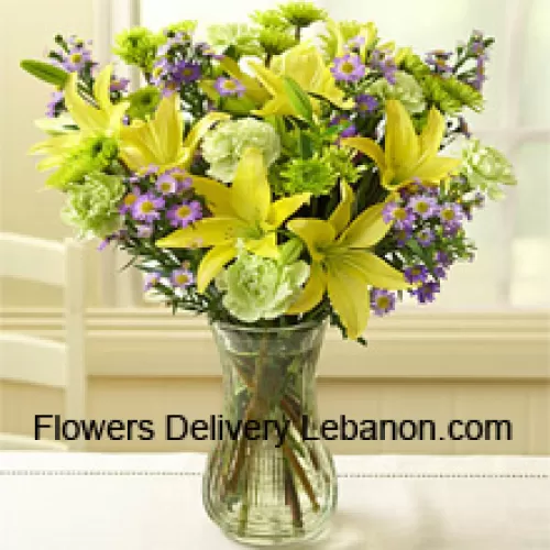 Lirios amarillos y otras flores variadas dispuestas hermosamente en un jarrón de cristal
