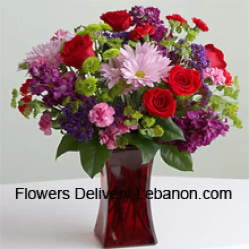 Rote Rosen, rosa Nelken und andere verschiedene saisonale Blumen in einer Glasvase