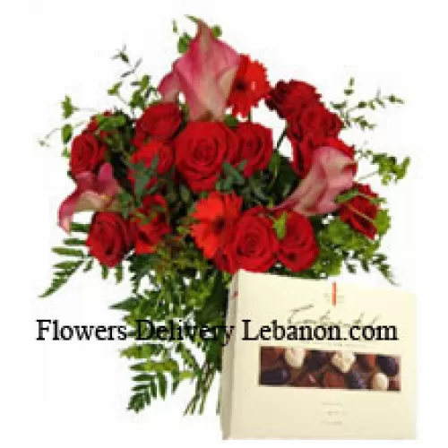 Rote Gerberas und rote Rosen in einer Vase zusammen mit einer Schachtel Schokolade