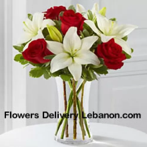 Rosas rojas y lirios blancos con algunos rellenos estacionales en un jarrón de cristal