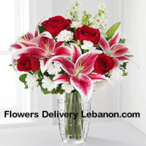 Rosas rojas, lirios rosados con flores blancas variadas en un jarrón de cristal